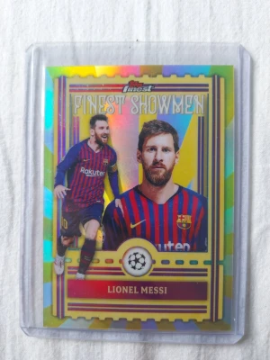 Finest Showmen Lionel Messi kort - Säljer ett samlarkort från Topps Finest Showmen med Lionel Messi i Barcelona-tröja. Kortet har färgglad, glittrig design och visar Messi i matchställ med rödblåa ränder. Perfekt för dig som samlar på fotbollskort eller älskar Champions League.
