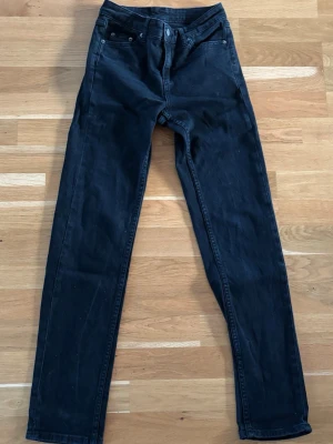 Svarta slim fit jeans  - Snygga svarta slim fit jeans från med klassisk femficksdesign och normalhög midja. Jeansen har raka ben och är tillverkade i ett stretchigt material för extra komfort. Perfekta för en trendig och avslappnad stil. Mått: 25/30