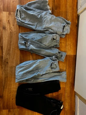 Fyra par jeans i olika tvättar - Säljer fyra par jeans i olika färger, tre ljusblå och ett svart. Några av jeansen har slitningar och fransiga detaljer vid benslut och knän, ett par har även en slits under rumpan som detalj. Perfekta för en avslappnad och trendig stil.  Priset är för alla tillsammans 