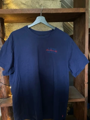 Mörkblå t-shirt från Levi's - Snygg mörkblå t-shirt från Levi's med liten röd logga på bröstet. Klassisk rund hals och korta ärmar. Tillverkad i mjuk bomull och har en relaxed passform som ger en chill vibe. Perfekt till jeans eller shorts.