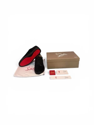 Svarta Christian Louboutin sneakers - Snygga svarta sneakers från Christian Louboutin med klassisk röd sula. Skorna har en låg profil, svarta skosnören och ovandel i mocka. Perfekta för dig som vill sticka ut med exklusiv design och ikoniska detaljer.
