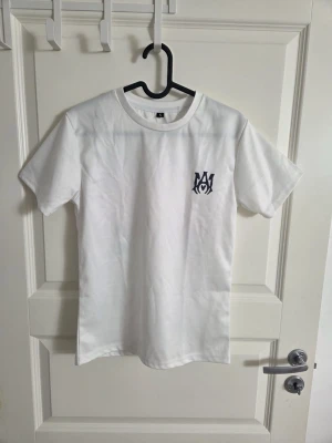 Vit t-shirt med tryck fram - Klassisk vit t-shirt i bomull med rund hals och korta ärmar. På bröstet finns ett svart tryck som ger en cool detalj till den annars enkla designen. Perfekt till jeans eller shorts för en avslappnad look.