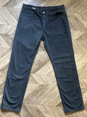Svarta Levi's 541 - Säljer ett par svarta jeans med rak passform och klassisk femficksdesign. Jeansen har bälteshällor, knappgylf och är tillverkade i ett mjukt denimtyg. Perfekta för dig som gillar en enkel och stilren look. Längd 110cm Bredd 45cm
