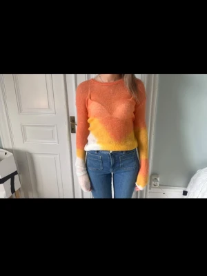 Flerfärgad topp - Säljer en tunn och fluffig stickad topp i mohairmix med färgskiftningar i orange, gult och vitt. 