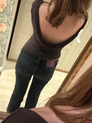 Brun långärmad topp med öppen rygg - Säljer en mörkbrun långärmad topp med en djup öppen rygg. Toppen har en tight passform och är perfekt för dig som vill ha en enkel men ändå snygg look. Materialet känns mjukt och stretchigt, troligen bomull eller polyester.