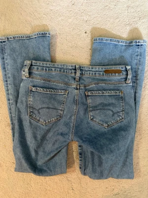 Ljusblå raka jeans med fem fickor - Säljer ett par klassiska ljusblå jeans med raka ben och fem fickor. Jeansen har normal midja, bälteshällor och subtila sömdetaljer på bakfickorna. Perfekta för en avslappnad och trendig look.