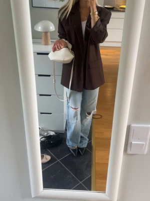 Baggy jeans Zara  - Säljer ett par ljusblå jeans med raka ben och slitningar på knäna. Jeansen har låg midja och full längd, vilket ger en avslappnad och trendig look. Perfekta för dig som gillar en casual och edgy stil.