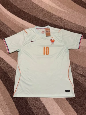 Frankrike 2026 bortatröja  - Frankrike 2026 bortatröja  Storlek: XXL Namn och nummer: MBAPPÉ #10 Badge: Ingen  Beskrivning: Numret där framme är lite sne och inte precis i mitten.  Säljs av ICEKIT icekit.se