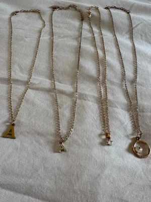 Smyckesset med Fyra guldhalsband - Säljer ett fint smyckesset med fyra tunna guldfärgade halsband med olika berlocker!😍Två halsband med bokstaven ’A’ (en utan detaljer & en med små stenar), ett halsband med en liten klar sten, och ett med en rund cirkelberlock & klar sten inuti🤍Perfekta för att mixa och matcha till olika outfits! Passar bra för alla tillfällen, vardagligt eller fest🩷Använda några gånger men alla är utan fel. (Halsband 4 har tappat lite färg på cirkeln). Hör av vid frågor/bud, bundle rabatt❤️Mer smycken➡️min profil.