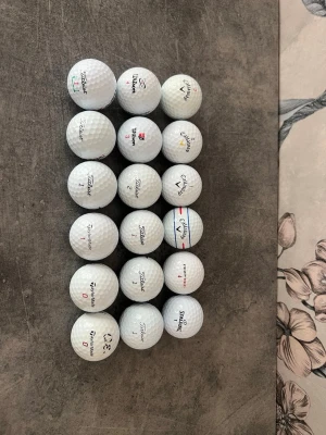 18 st golfbollar Titleist Callaway Wilson och annat - Säljer 18 golfbollar från Titleist, Callaway, Wilson och några andra märken. Alla bollar är klassiskt runda med dimple-mönster och har tryckta loggor och siffror i svart och rött. Perfekt för dig som vill fylla på golfbagen med blandade märken. Bollarna är ungefär klass C det finns några bättre men det är mest klass C bollar.