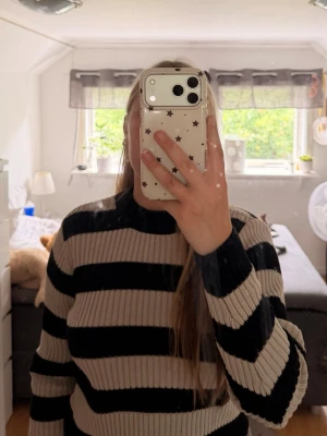 Stickad Tröja  - Säljer en ribbstickad tröja med breda svarta och beige ränder. Tröjan har rund halsringning och långa ärmar. Perfekt för dig som gillar en enkel men trendig look. Materialet känns mjukt och stretchigt, vilket gör den bekväm att bära passar mig som har S. Knappt aldrig använd. 