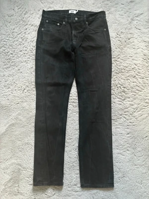 Svarta raka jeans från 157 - Svarta jeans med rak passform och klassisk femficksdesign från 157. Jeansen har normal midja och är tillverkade i ett mjukt denimtyg. Perfekta för en stilren och enkel look.