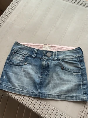 Blå jeanskjol med fickor - Säljer en kort blå jeanskjol som ör rosa på insidan och har slitningar och fem fickor från Pull & Bear. har inga som helst defekter, pris kan diskuteras ❤️
