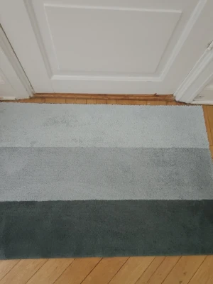 Randig matta i grå toner 89,5 x 60 cm - Säljer en rektangulär matta med tre breda ränder i olika grå nyanser. Mattan har en mjuk och fluffig yta som passar perfekt i hallen eller sovrummet. Enkel och stilren design som smälter in i de flesta hem. Tvättad och färdig till nästa hem . Från rökfritt och DJURFRITT hem.