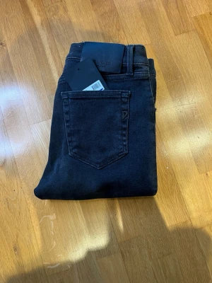 Svarta Dondup jeans - Snygga svarta jeans från Dondup med klassisk femficksmodell och raka ben. Jeansen har en diskret logga på bakfickan och är tillverkade i mjukt denimtyg som ger en skön passform. Perfekta för dig som gillar stilrena och tidlösa plagg.