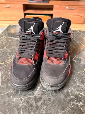 Svarta och röda Air Jordan 4 sneakers - Air Jordan 4 Red Thunder + box   Säljer mina Air Jordan 4 Red Thunder. Använda men i väldigt bra skick, inga stora skador – bara normalt slitage. Fortfarande riktigt fräscha och sticker ut, perfekt till outfit.  Kommer med originalbox. Den här modellen är eftertraktad och säljs snabbt när de är i så här bra skick.  Storlek: 43 Pris: 2500 kr (öppen för seriösa bud)  Först till kvarn – kan mötas upp eller skickas.