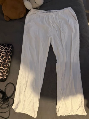Vita linnebyxor från 157 - Säljer ett par vita linnebyxor från 157 med avslappnad passform med låg midjan. Byxorna har raka ben och sidofickor, perfekta för en chill och stilren look. Materialet är lätt och luftigt linne.