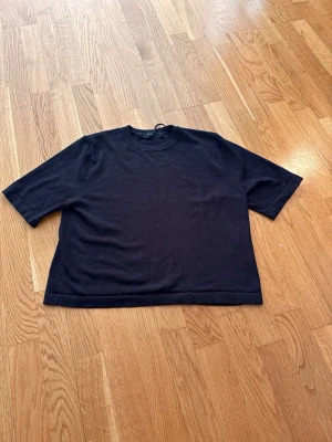 Svart loose stickad topp - En svart stickad topp med rund hals och halvlånga ärmar. Modellen är loose fit och har en enkel, rak design som gör den lätt att styla till olika looks. Perfekt för dig som gillar minimalistiska plagg.