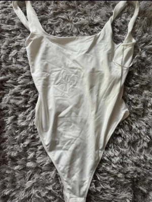 Vit body med breda axelband XS - Säljer en stilren vit body från GINATRICOT i storlek XS. Bodyn har breda axelband, rundad halsringning och är tillverkad i mjukt stretchigt material.  Helt oanvänd 