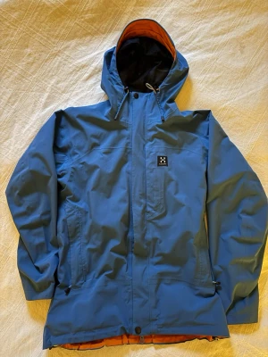 Blå jacka från Haglöfs dam M - Snygg blå gore-tex jacka från Haglöfs med orange innerfoder och svart mesh. STORLEK 38. Superbra skick