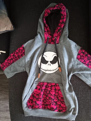 hoodie med döskalle - grå hoodie med stor vit döskalle på bröstet och döskallemönster på huva, ficka och ärmar. Perfekt för dig som gillar edgy och alternativ stil. Mjuk och varm insida. Köpt på ett event. Pris kan diskuteras 💕