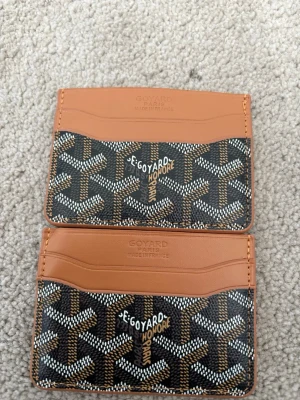  brun kortfodral i läder - Säljer ett stilrent kortfodral  i brunt och svart med det klassiska '. Fodralet har flera kortfack och är tillverkat i läder och canvas. Perfekt för dig som vill ha en exklusiv accessoar i fickan.