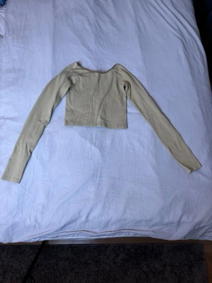 Set, beige ribbade leggings med utsvängda ben och tillhörande topp  - Snyggt tvådelat set i beige ribbat material med långärmad, croppad topp och matchande utsvängda byxor med hög midja. Perfekt för en trendig och bekväm look. Materialet är stretchigt och följsamt.