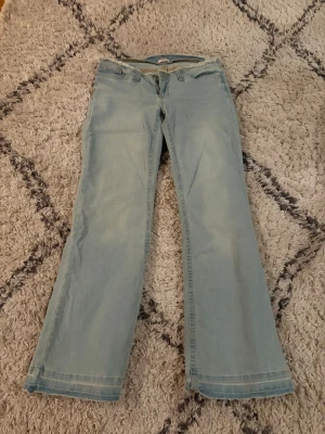 Ljusblå bootcut jeans från Nelly - Snygga ljusblå jeans från Nelly med bootcut-modell och råa kanter upptill. Jeansen har klassisk femficksdesign och stängs med dragkedja och knapp. Perfekta för en avslappnad och trendig look.