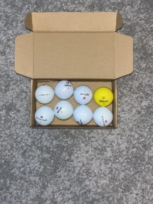 Wilson mix A/B klass  - Säljer en låda med 8 golfbollar i vitt och en i gult. Bollarna är av olika märken, bland annat Wilson och några med texten Wilson Ultra. Perfekt för dig som vill fylla på golfväskan med extra bollar i olika färger.