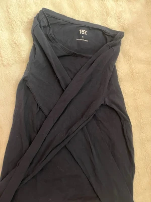 Svart långärmad topp från 157 - En svart långärmad topp från 157 i mjuk bomullsblandning med 5% elastan för extra stretch. Enkel och stilren design som passar till det mesta. Perfekt basplagg i garderoben.