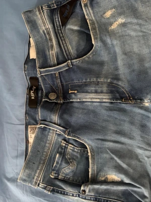 Ljusblå slitna jeans från Replay - Säljer ett par ljusblå jeans från Replay med skinny fit och flera slitningar och hål på benen.