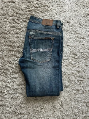 Nudie jeans - Hej, säljer nu ett par Nudie jeans i fin färg med snygga slitningar. Jeansen är i storlek W34 och passar slimfit. Skriv vid fler funderingar!