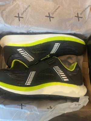 2x 44 1x 42 - Snygga svarta sneakers med neongula och vita detaljer. Skorna har en sportig design med meshpaneler och reflekterande mönster på sidorna. Tjock vit sula och neongult foder ger en modern look. Perfekta för dig som gillar streetstyle.