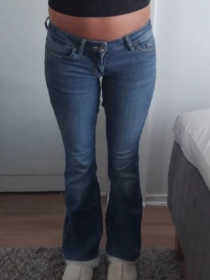 Blå bootcut jeans med låg midja - Säljer ett par blå bootcut jeans med låg midja och klassiska fem fickor. Jeansen har en snygg tvätt och lätt utsvängda ben. Jag som säljer har sytt dom till lågmidjade och det har gjort att dom sitter lite extra tight runt låren. Står XS men skulle säga XXS. (Se bild 4,5) Uppsydda av ägaren innan. (Se bild 3) Defekter på bakfickor. (Se bild 6)