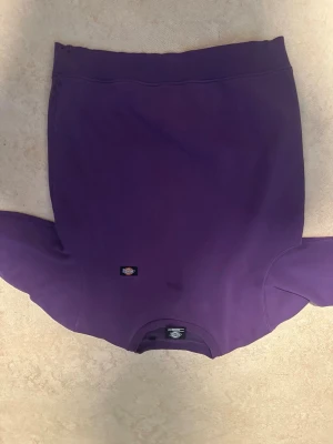 Lila sweatshirt från Dickies - En stilren lila sweatshirt från Dickies med rund halsringning och diskret logga på bröstet. Tröjan har en klassisk passform och är tillverkad i mjukt material som passar perfekt till en avslappnad look.
