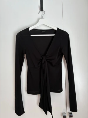 Svart långärmad topp Gina Tricot - Trendig svart långärmad topp från Gina Tricot med snygg knytning framtill. Jag har använt den ca 2 gånger så är i ett superbra skick. Den är tunn och i storlek xs, köpte förra året.