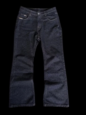 Mörkblå bootcut jeans - Snygga mörkblå jeans med bootcut passform och klassisk femficksdesign. Jeansen har hög midja och raka ben som blir vidare nedtill. Tillverkade i kraftigt denimtyg som ger en tidlös look. Perfekta för dig som gillar en retrostil.