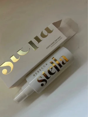Rebecca Stella Coco Daze Tan Mist - Fräsch face mist från Rebecca Stella i serien Coco Daze Tan Mist. Flaskan är vit med elegant guldtext och har en praktisk sprayfunktion. Kommer i matchande vit förpackning med guldiga detaljer. Perfekt för en återfuktande och glowig känsla.