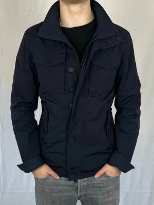 J.Lindeberg Field jacket - Mörkblå  J.Lindeberg field jacket i storlek m. Jackan är i väldigt bra skick och perfekt till våren! Vid frågor eller funderingar är det bara att höra av sig!