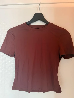 Mörkröd basic t-shirt - En enkel mörkröd t-shirt med rund hals och korta ärmar. Modellen är figurnära och passar perfekt till jeans eller kjol. Tillverkad i mjukt material som känns skönt mot huden.