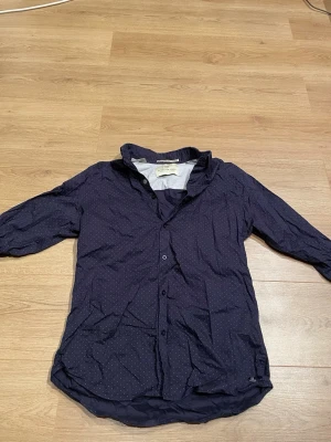 Mörkblå prickig skjorta Scotch & Soda - Snygg mörkblå skjorta från Scotch & Soda med små vita prickar. Skjortan har knappar framtill, klassisk krage och trekvartsärm. Perfekt för dig som gillar stilrena detaljer och en avslappnad look.