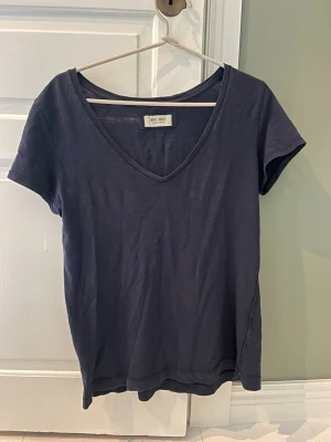 Mörkblå v-ringad t-shirt - En enkel och stilren mörkblå t-shirt med v-ringning och korta ärmar. Tillverkad i mjuk bomull som känns skön mot huden. Perfekt basplagg till alla outfits. Osäker på storlek men skulle säga S-M. Köpt för 600