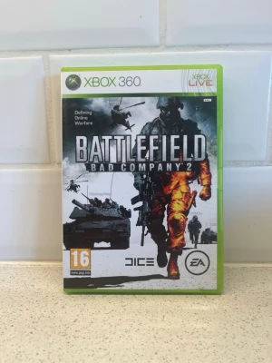 Battlefield Bad Company 2 Xbox 360 - Battlefield Bad Company 2 till Xbox 360 är ett actionfyllt FPS-spel från EA och DICE. Omslaget är grönt och spelet har militärtema med soldater, stridsvagnar och helikoptrar på framsidan. Perfekt för dig som gillar intensiva onlinestrider och taktiskt lagspel. Fungerar toppen!
