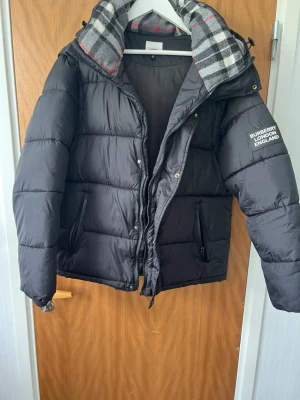 Svart pufferjacka från Burberry - Ganska ny men blev använd mycket. Den  kan inte stängas men bara  med knapparna. Ena fickan kan inte stängas och har små problem. De står storleken är S men den är M  De 