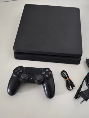 PlayStation 4 Slim med handkontroll - Säljer en svart PlayStation 4 Slim från Sony. Konsolen har en stilren, rektangulär design i matt plast och kommer med en svart DualShock 4-handkontroll samt tillhörande kablar. Perfekt för gaming och underhållning hemma.