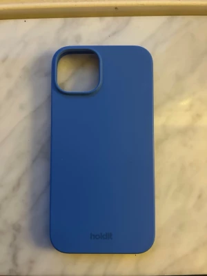 Blått mobilskal från Holdit, IPhone 14  - Snyggt blått mobilskal från Holdit med stilren design. Skalet är gjort i mjukt silikonmaterial och har en slät yta. Perfekt passform för din mobil och skyddar mot repor och stötar. Enkel att ta på och av. För IPhone 14