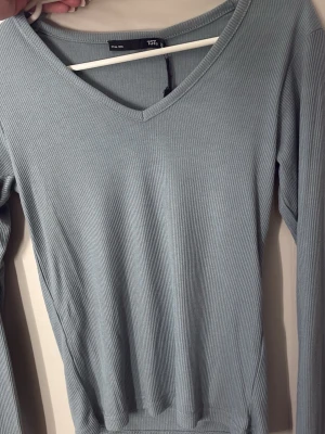 Ljusgrönribbad långärmad topp - Säljer en ljusgrön ribbad långärmad topp i storlek XS. Toppen har v-ringning och är tillverkad i ett mjukt, stretchigt material som sitter snyggt. Har även samma tröja i en beige färg, finns i min profil!