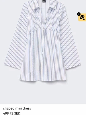 Vit och blå randig skjortklänning - Snygg kort skjortklänning med vertikala blå och vita ränder. Klänningen har v-ringning, krage och långa ärmar. Perfekt för en trendig och avslappnad look.
