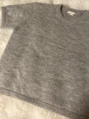 Grå stickad t-shirt - Säljer en stickad grå t shirt som jag aldrig användit då den inte är min stil. Den är i storlek 158/164 men passar mig som har storlek S (34-36)  i det mesta. Den är inte nopprig eller något eftersom den inte är använd - sista bilden visar lite bättre. Den är ljus grå men har tyget ändrar lite mellan en mörkare grå och ljus grå. Skriv till mig om du är intresserad