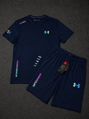 Mörkblått träningsset från Under Armour - Snyggt mörkblått träningsset med t-shirt och shorts från Under Armour. Setet har färgglada loggor och tryckdetaljer i regnbågsfärger. Materialet är lätt och andas, perfekt för träning eller sportaktiviteter. Elastisk midja på shortsen för skön passform.